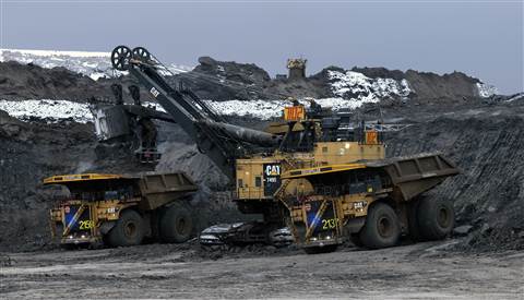 Two Cat 797F autonomous trucks   being loaded in pit